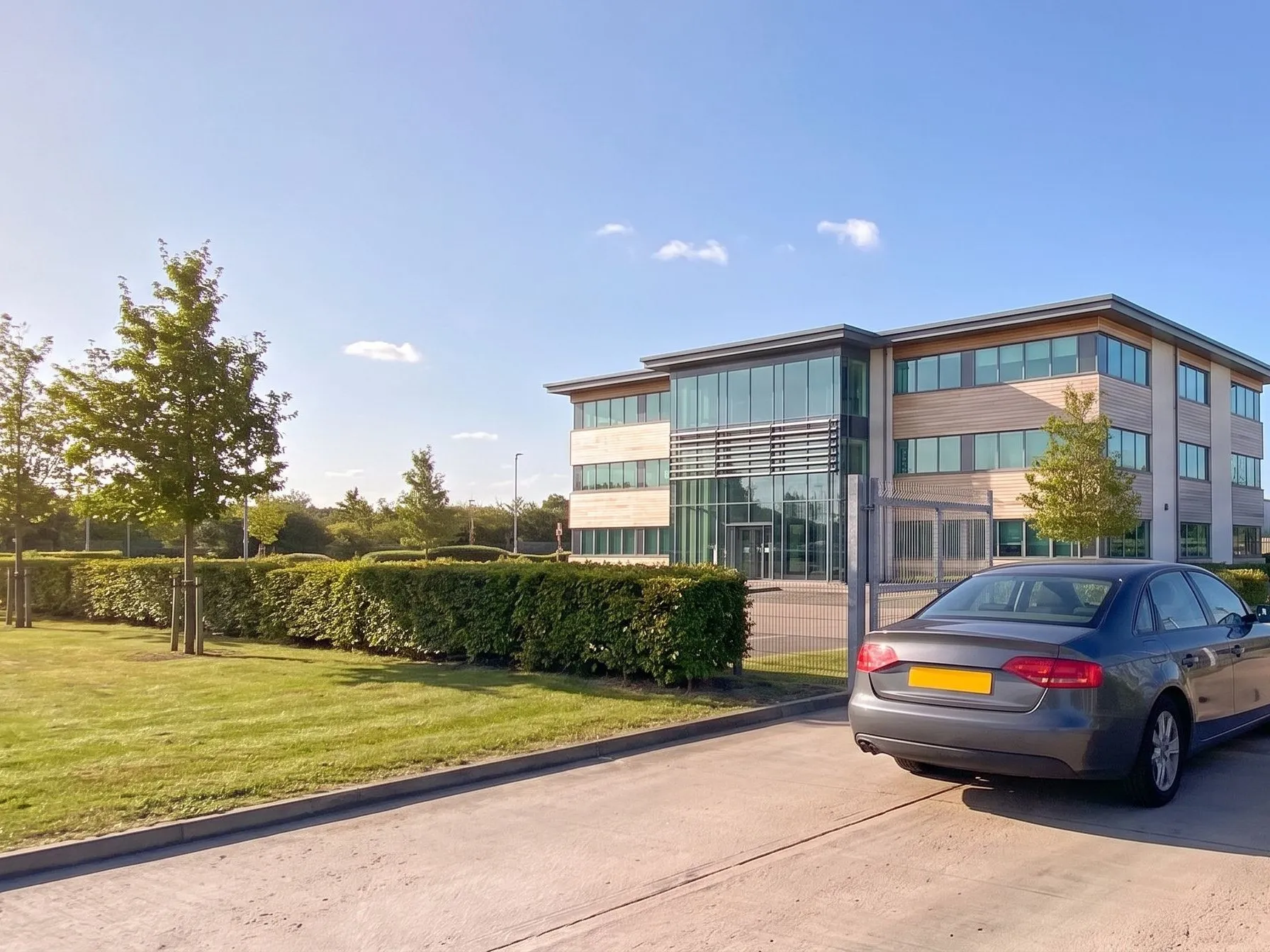 Modern glass and timber office building across a landscaped verge at a business park