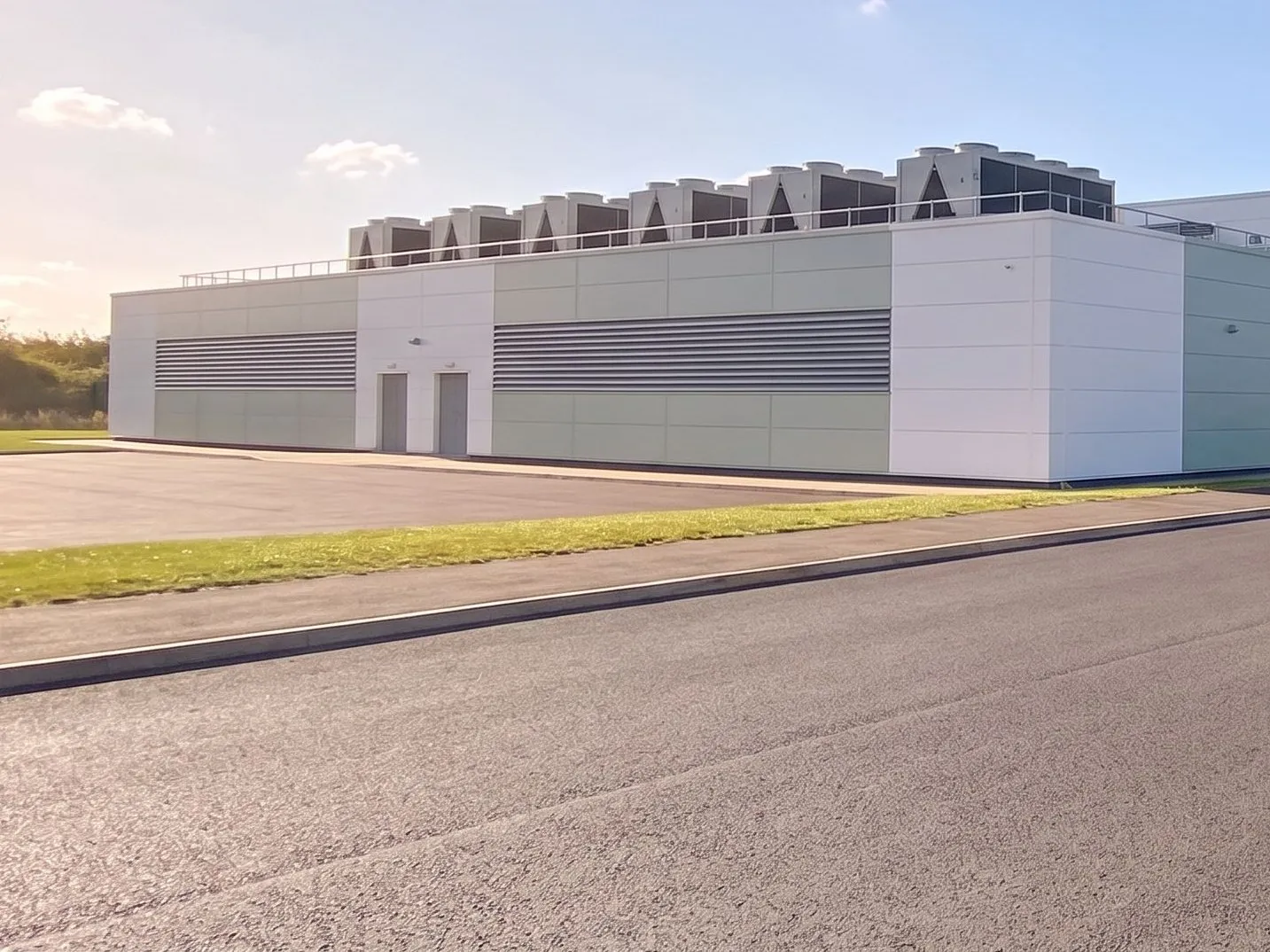 Data centre building with cooling units on its roof, beside the site access road